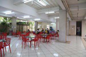 um restaurante com cadeiras e mesas vermelhas e pessoas ao fundo em Alicia Tower Residences em Cebu