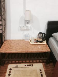 uma mesa com uma chaleira ao lado de uma cama em Roomstay Zulmi em Arau