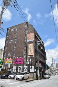a large building with cars parked in front of it at Kumoji-so Hostel in Naha