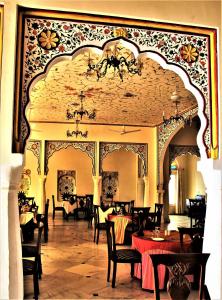 a dining room with tables and chairs and a chandelier at Sanchal Fort in Bārmer
