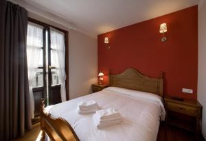 a bedroom with a white bed with a red wall at Casa Rural Maialde in Elgeta