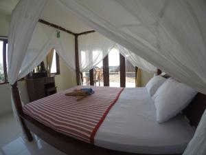 a bedroom with a bed with a canopy at Homestay & Restaurant Segara Amed in Amed