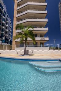 una piscina con una palmera frente a un edificio en Wyuna Beachfront Holiday Apartments, en Gold Coast
