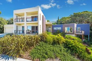 a house on a hill with plants in front of it at Kilala - executive home in Port Macquarie