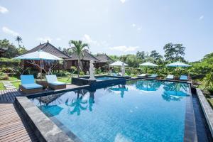 einen Pool in einem Resort mit Stühlen und Sonnenschirmen in der Unterkunft The Cubang Hut's Lembongan in Nusa Lembongan