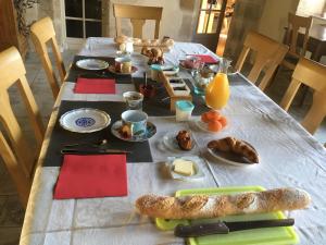 una mesa con alimentos para el desayuno y zumo de naranja en ella en La Troliere, en Autry-Issards