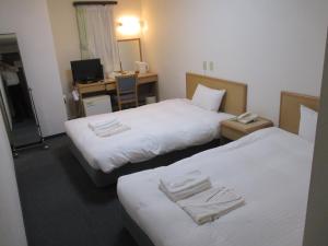 a hotel room with two beds and a desk at Hotel Green Well in Sendai