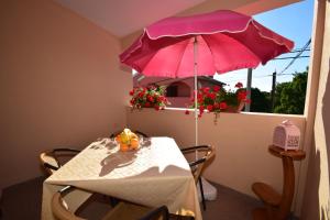 a table with a pink umbrella in front of a window at Apartment Smokrovic in Starigrad