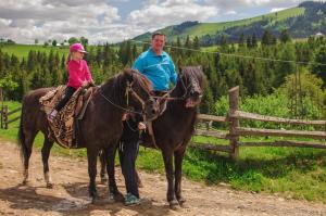 een man en een klein meisje zittend op een paard bij Polonyna in Verkhovyna