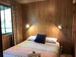 Un dormitorio con una cama con paredes de madera y una ventana en Colac Colac Caravan Park en Corryong