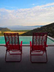 two red chairs sitting on a balcony with a view at Red Grey Sea View Villa in Schinias