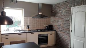 a kitchen with a brick wall and a stove top oven at Hoeve Schevey in Mechelen