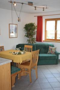 uma sala de estar com uma mesa e um sofá verde em Ferienwohnungen Franz Pfeifer / Beatrice Roduner em Gaschurn