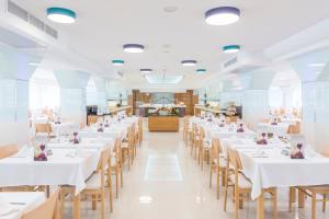 une grande salle à manger avec des tables et des chaises blanches dans l'établissement Hotel Vista Park, à Can Picafort