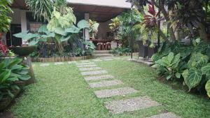 a garden with grass and stepping stones and plants at Puri Cantik in Ubud