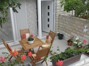 eine Terrasse mit einem Tisch, Stühlen und Topfpflanzen in der Unterkunft Apartmani Lucija in Zadar