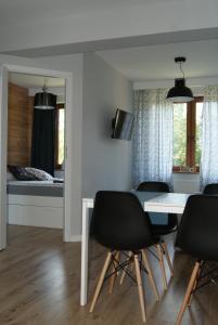 jadalnia ze stołem i krzesłami oraz sypialnia w obiekcie Apartament Gratka w Dziwnówku