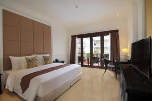 a bedroom with a large bed and a television at Grand Palace Hotel Sanur - Bali in Sanur