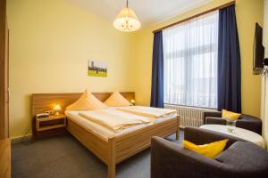 um quarto de hotel com uma cama e uma cadeira em Hotel Graf Waldersee em Borkum
