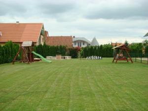 einen großen Garten mit zwei Schaukeln und einem Spielplatz in der Unterkunft Eman Apartmanház in Bük