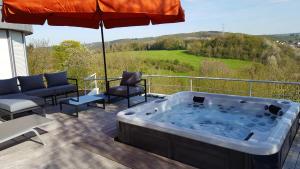 - un bain à remous sur une terrasse avec un parasol dans l'établissement PepinSphair, à Pepinster