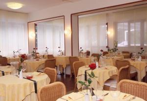 une salle à manger avec des tables, des chaises et un tissu de table blanc dans l'établissement Hotel Mar Del Plata, à Grado