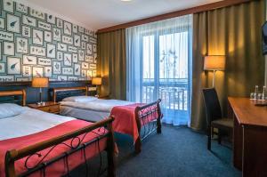 a hotel room with two beds and a desk and a window at Resort Strzelnica in Kochcice