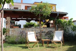 two chairs sitting in the grass in front of a house at Apartment Dragun in Pula