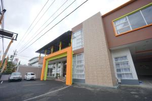 un edificio con una porta arancione e auto parcheggiate fuori di The Cabin Tanjung Hotel Wonosobo a Wonosobo