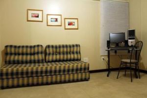 a living room with a couch and a desk with a computer at Hotel Bela Vista in Paranoá