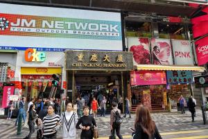 un grupo de personas caminando por una concurrida calle de la ciudad en New Grand Guest House, en Hong Kong