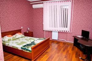 a bedroom with a bed and a desk and a window at Gostevoy Apartment in Vinnytsya