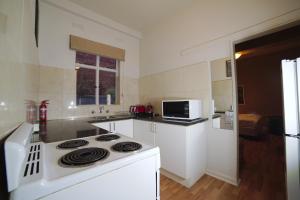 a white kitchen with a stove and a microwave at City Centre Budget Hotel in Melbourne