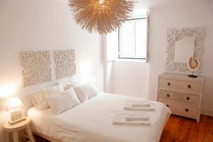a bedroom with a white bed with a mirror and a chandelier at Old Fence Studios - By Mayoral in Lisbon