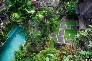 einen Garten mit einem Pool mit Bäumen und Pflanzen in der Unterkunft Rumah Roda in Ubud