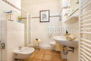 ein weißes Bad mit einem Waschbecken und einem WC in der Unterkunft Villa Hildegard by Callsen in Binz