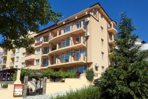 an apartment building with balconies and a tree at Family Hotel Milev in Sveti Vlas