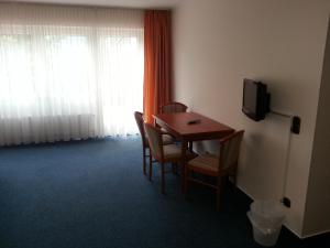 Cette chambre dispose d'une table, de chaises et d'une télévision. dans l'établissement Schmucker Jäger - Hotel Garni, à Hann. Münden