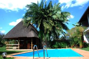a resort with a palm tree and a swimming pool at Hotel Le Garni in Kigali