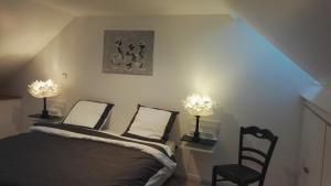 a bedroom with a bed and a chair and two lights at les Bovrieres in Cysoing