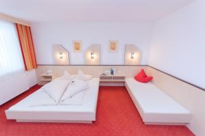 レンゲンフェルトにあるApart Alpenerlebnisの白いベッド2台と赤いカーペットが備わる客室です。