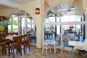 a dining room with a table and chairs and windows at Family Hotel Milev in Sveti Vlas