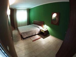 1 dormitorio con pared verde, cama y ventana en Djasal Moradias Apartment, en Santa Maria