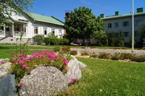 une maison avec des fleurs roses dans une cour dans l'établissement Kartanohostel AnnaCatharina, à Savonlinna