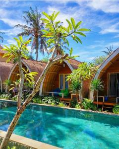 a resort with a swimming pool and palm trees at Paradesa Villa in Gili Trawangan