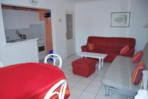 a living room with a red couch and a kitchen at Appartement La Baule Plage in La Baule