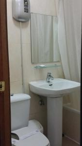 a bathroom with a sink and a toilet and a mirror at Hostal Lima in Valladolid