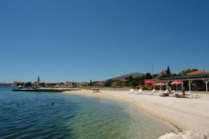 ein Strand mit Stühlen und Sonnenschirmen und Menschen im Wasser in der Unterkunft Apartment Nane in Trogir + 5 Fotos