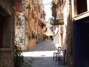an alley with two chairs in an alley between buildings at Lito Rooms in Chania