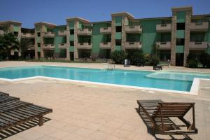 a swimming pool with two chairs and a building at Djasal Moradias Apartment in Santa Maria